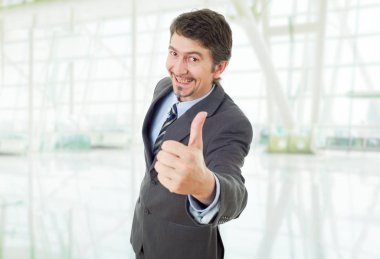 Genç iş adamı ofiste başparmağını kaldırıyor.