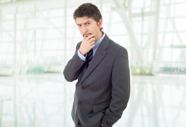 Genç bir iş adamı, ofiste düşünüyor.