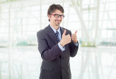 Mutlu iş adamı ofiste başparmağını kaldırıyor.