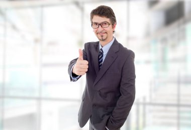 Genç iş adamı ofiste başparmağını kaldırıyor.