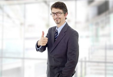 Mutlu iş adamı ofiste başparmağını kaldırıyor.