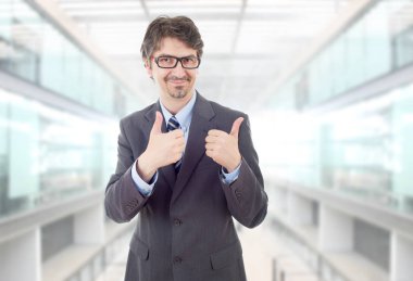 Mutlu iş adamı ofiste başparmağını kaldırıyor.