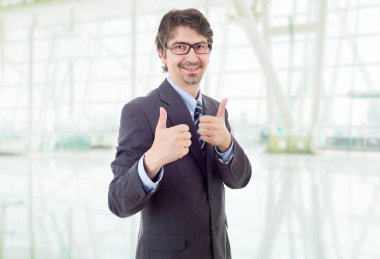 Genç iş adamı ofiste başparmağını kaldırıyor.