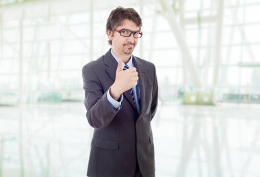 Genç iş adamı ofiste başparmağını kaldırıyor.