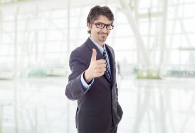 Genç iş adamı ofiste başparmağını kaldırıyor.