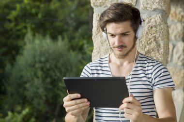 Kulaklıklı, açık havada müzik dinleyen genç adam.