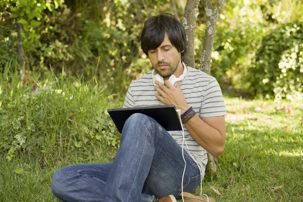 Νεαρός Άνδρας Χαλαρωτικό Ένα Tablet Ακούγοντας Μουσική Ακουστικά Για Ένα — Φωτογραφία Αρχείου