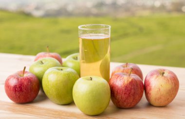 Elma ve elma suyu ahşap bir masada, açık havada.