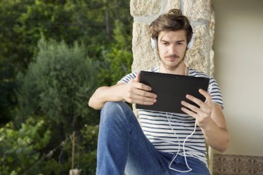 genç adam bir kulaklık, açık ile müzik dinleme tablet pc ile rahatlatıcı