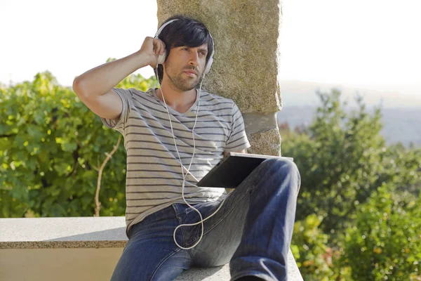 Jeune Homme Travaillant Avec Une Tablette Écouter Musique Avec Écouteurs — Photo