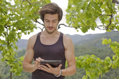 Genç adam bir tablet pc ile rahatlatıcı üzerinde bir park, açık