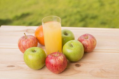 Bir bardak portakal suyu ve tahta masada bir sürü meyve.