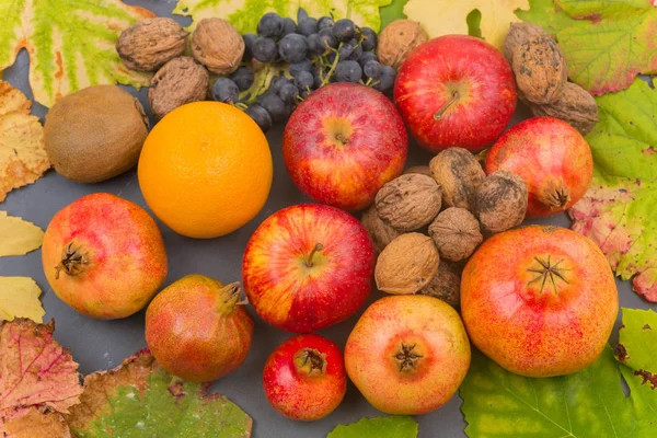 Осенние фрукты натюрморт среди листьев на деревянном столе — стоковое фото