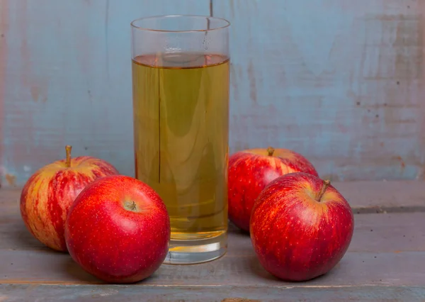 Un vaso de jugo de manzana y unas manzanas rojas — Foto de Stock