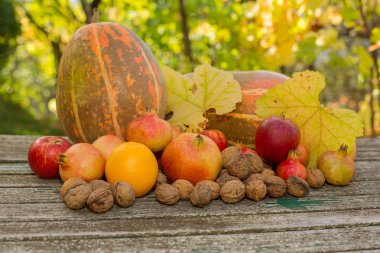 Sonbahar meyveleri ahşap bir masada, açık havada.