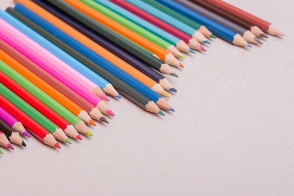 Drewniane kolorowe ołówki, na szarym papierze — Zdjęcie stockowe