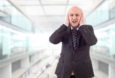 Yakışıklı iş adamı, ofiste gürültü yapmadan kulaklarını kapatıyor.