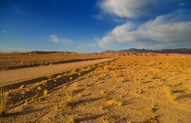 Güney İran, Kerman yakınlarındaki dağların altında çöl yolu.