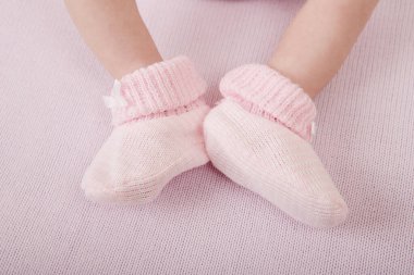 Yeni doğmuş bebek ayakları yakın çekim. Beyaz çoraplı bebek ayakları, yatakta yatan bebek