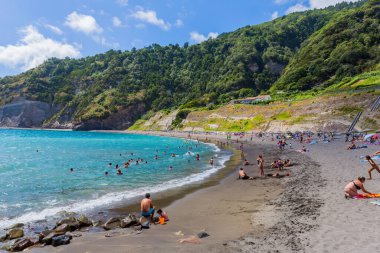 Ribeira Quente, Sao Miguel Adası, Azores, Portekiz: İnsanlar denizde yüzüyor ve Ribeira Quente kasabasının oradaki Praia do Fogo kumsalında dinleniyorlar.