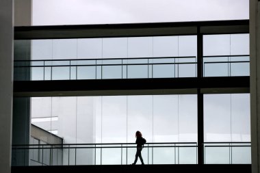 Modern ofis binasında panoramik pencereli genç bir iş kadınının silüeti..