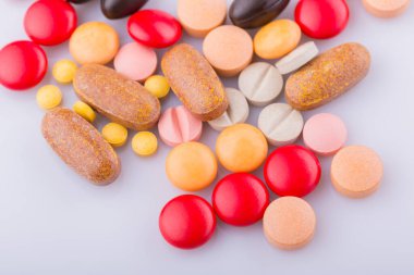 Haplar, kapsül yığını, karışık terapi ilaçları, beyaz bir arka plan.