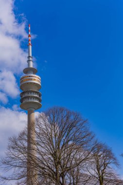 Münih, Almanya: Olympia Park 'taki Olympiaturm (Olympia Kulesi). Parkın ağaçlarından yukarı bakıyorum. Olimpiyat oyunları için yapılmış, Münih, Almanya