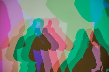 Renkli gölgeler, RGB aydınlatması boyunca duvara vurularak soyut ve sanatsal bir etkileşim yaratıyor insan siluetleri ve üst üste binen ışık.