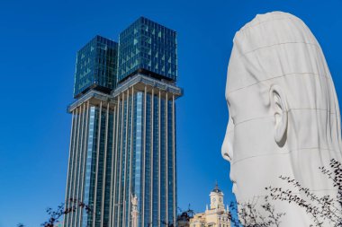 Madrid, Spain: Modern architecture and a giant head sculpture under clear blue skies in Madrids Plaza de Coln.
