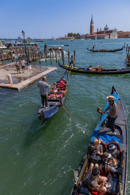 Venice, Italy: Gondolas glide through the Venetian canal as a gondolier rows past historic buildings