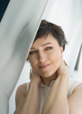 Kısa saçlı esmer bir kadının yakın plan portresi.