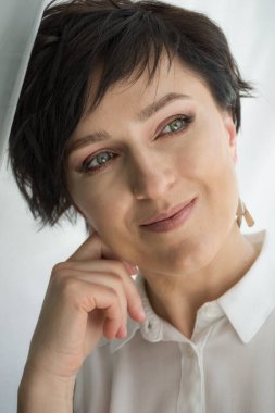 Kısa saçlı esmer bir kadının yakın plan portresi.