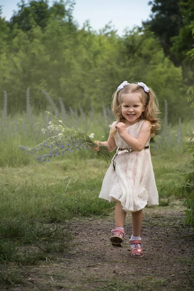 Küçük Kız Bir Buket Kır Çiçeğiyle Neşe Içinde Bir Patika — Stok fotoğraf