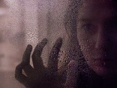 Islak bardağın arkasındaki bir kadının silüeti. Gerilim