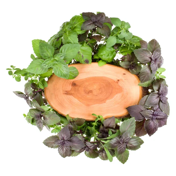 Wooden board over various sweet basil herb leaves background. He — Stock Photo, Image