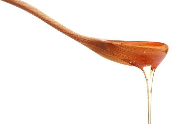 白い背中に分離された木製蜂蜜ディッパーから滴る蜂蜜 — ストック写真