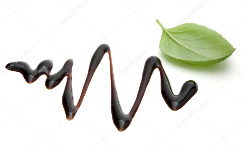 Balsamic vinegar cream and basil leaves isolated on white background. Italian salad dressing, sauce.