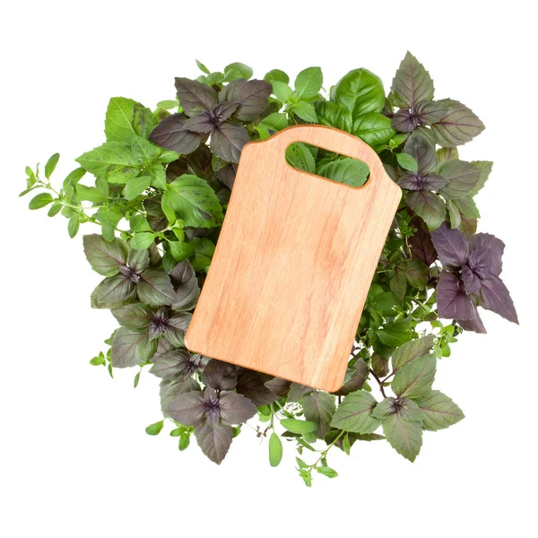Planche à découper en bois vide sur diverses feuilles d'herbes de basilic doux — Photo