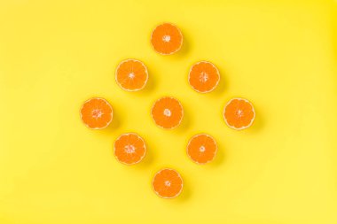 Taze mandalina dilimleri sarı zemin üzerine meyve deseni. Düz yatıyordu, en iyi görünüm. Pop sanat tasarım, yaratıcı yaz konsepti. Minimal tarzda narenciye yarısı. Mandalina.
