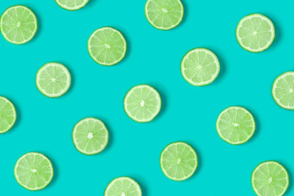 Fruit pattern of lime slices on blue background. Flat lay, top view.