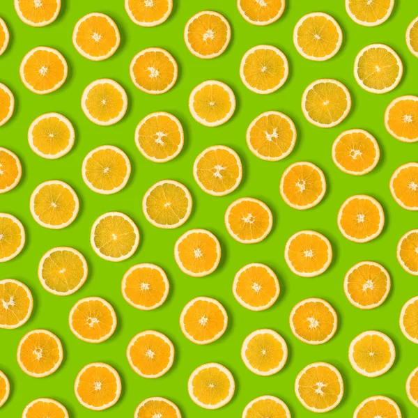 Fruit pattern of orange slices on green  background. Flat lay, top view. Food background.