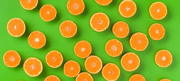 Fruit pattern of fresh orange slices on green background. Flat lay, top view. Pop art design, creative summer concept. Half of citrus in minimal style.