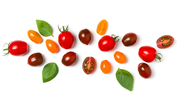 Verschiedene bunte Tomaten und Basilikumblätter isoliert auf weißem Bac — Stockfoto