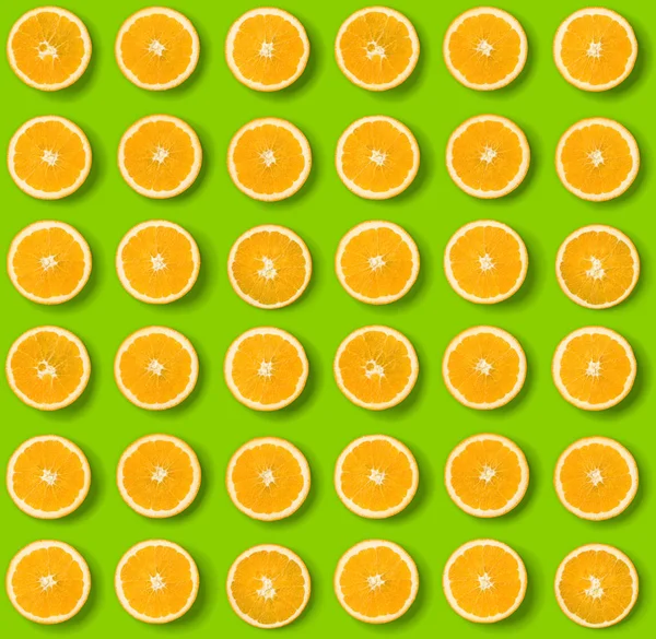 Fruit pattern of orange slices on green  background. Flat lay, t