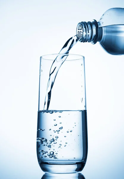 Pouring water into glass  from bottle on blue background