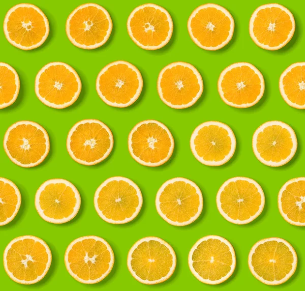 Seamless pattern of orange fruit slices on green background. Fla