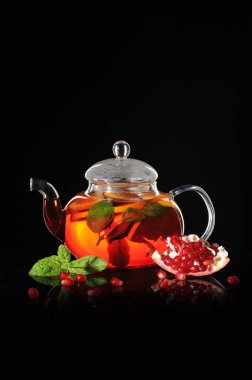Bir cam çaydanlık siyah bir zemin üzerine nar çay