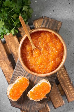 Ahşap kase gri bir arka plan üzerinde kırmızı havyar. Üstten görünüm