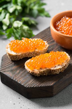 Gri arka plan üzerinde ahşap tahta üzerinde seramik kase kırmızı havyar