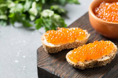 Gri arka plan üzerinde ahşap tahta üzerinde seramik kase kırmızı havyar